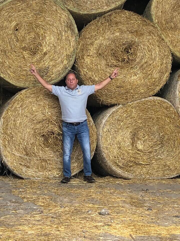 Hawley poses next to giant hay bales at Zuber Farms in Churchville, Monroe Co. where the owners produce corn, hay, wheat and dairy replacements.